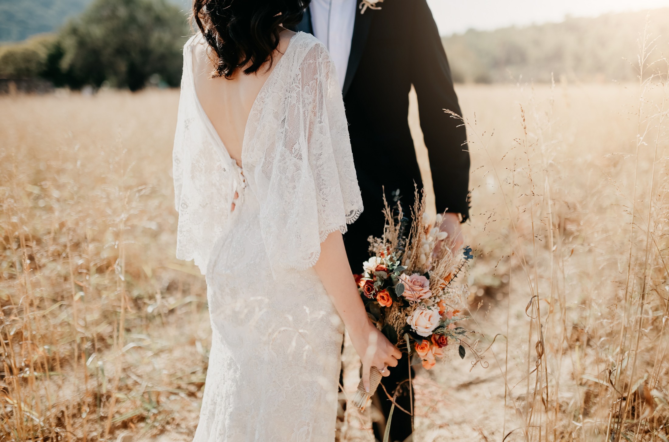 Novios abrazados en un campo dorado al atardecer