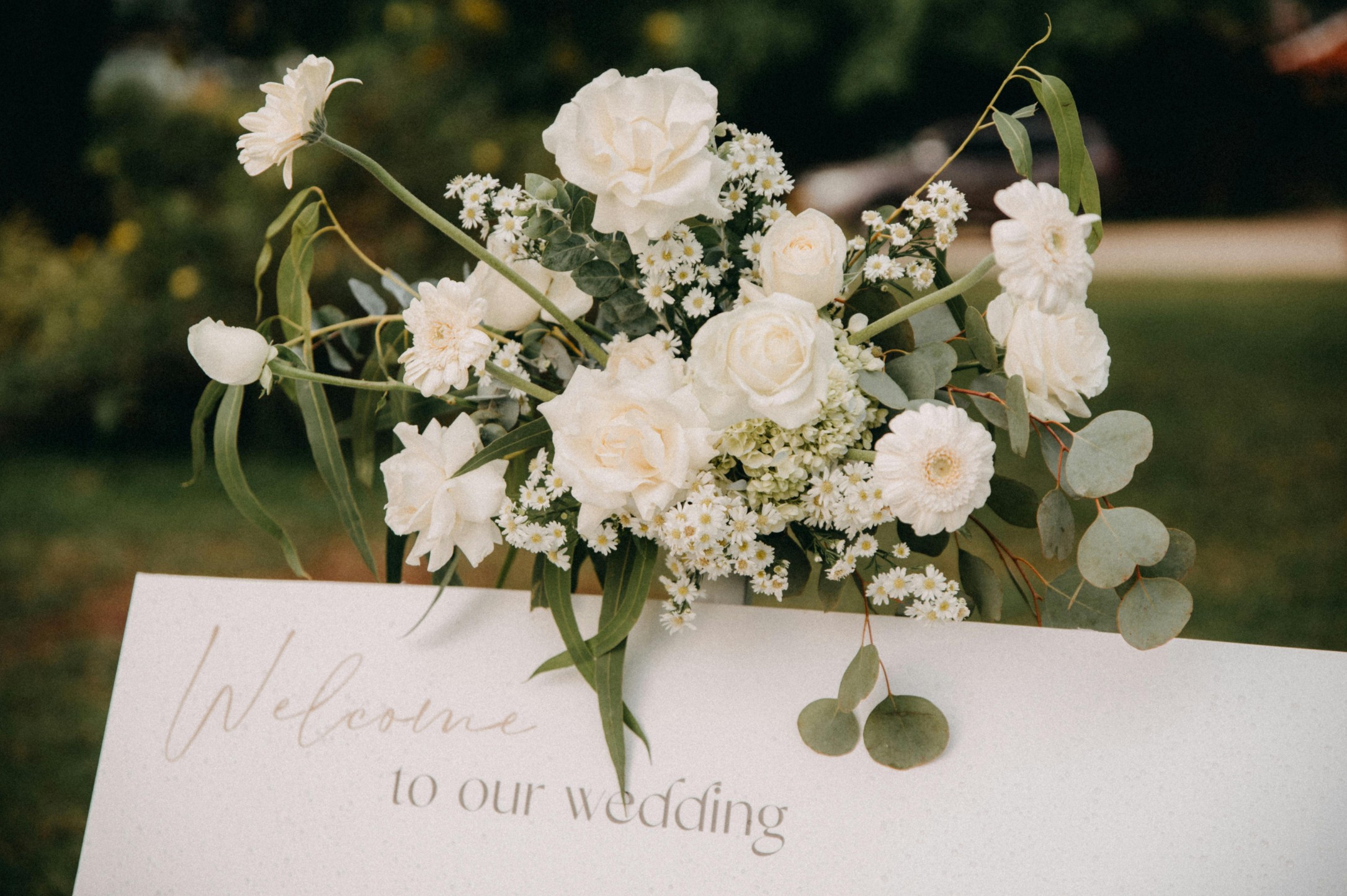 Ramo de novia sobre un cartel de bienvenida a la boda