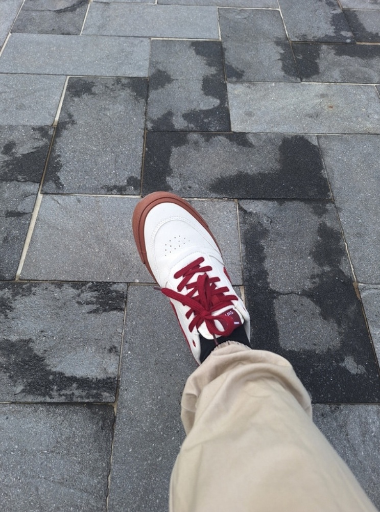 Zapatilla blanca con cordones rojos, vista desde arriba caminando